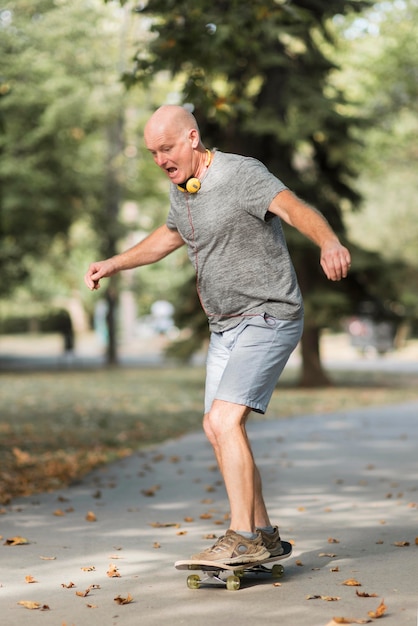 Homme de tir complet avec planche à roulettes dans le parc