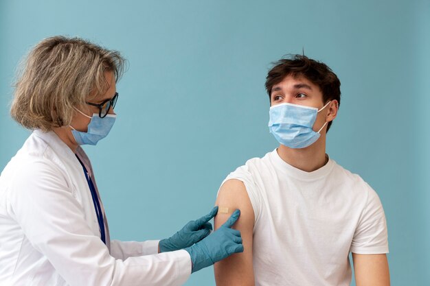 Homme de tir moyen avec un masque se vaccinant