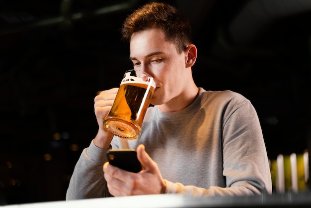 Homme de tir moyen avec téléphone et chope de bière