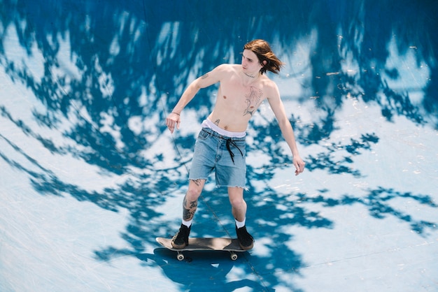 Homme torse nu, faire du skateboard sur une rampe
