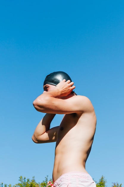 Homme torse nu portant bonnet de bain à l'extérieur