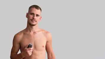Photo gratuite homme torse nu tenant un rasoir électrique avec espace copie