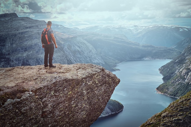 Homme de tourisme debout dans le Trolltunga et profite de la belle vue sur le fjord norvégien.