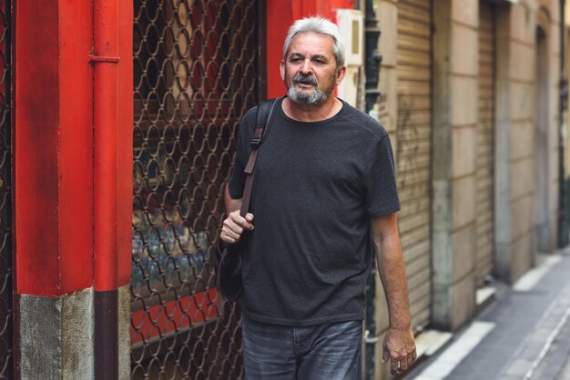 Homme touristique mûr avec sac à dos voyage en milieu urbain.