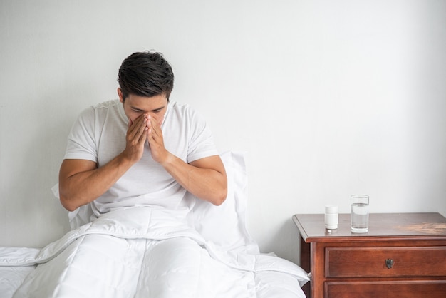 L'homme toussa, mit sa main sur sa bouche et s'assit sur le lit.