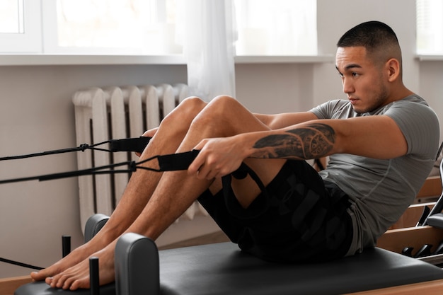 Photo gratuite un homme en train de suivre un cours de réformation du pilates.