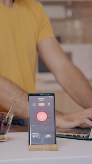 Homme travaillant à domicile avec un système d'éclairage automatisé utilisant la commande vocale sur un smartphone allumant la lumière