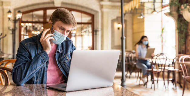 Homme travaillant à l'intérieur tout en portant un masque facial avec copie espace