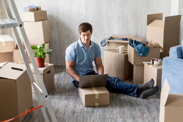 Homme travaillant sur ordinateur portable avec des boîtes prêtes à déménager