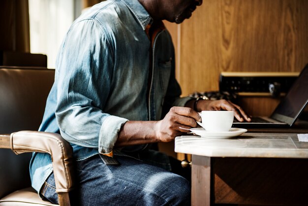 Homme travaillant sur un ordinateur portable et buvant une boisson chaude