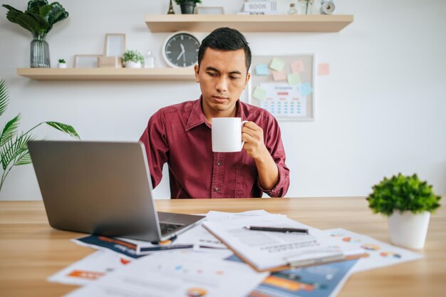 Homme travaillant avec un ordinateur portable et tenant une tasse de café