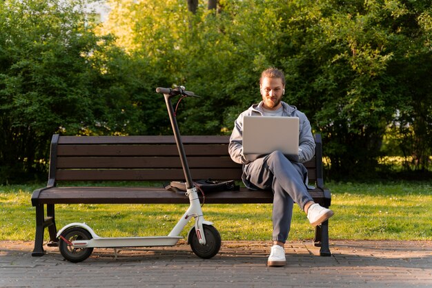 Homme travaillant sur son ordinateur portable à côté de son scooter