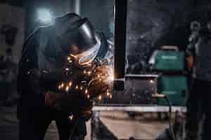 Photo gratuite l'homme travaille dans une usine métallurgique, il soude un morceau de rail à l'aide d'outils spéciaux.