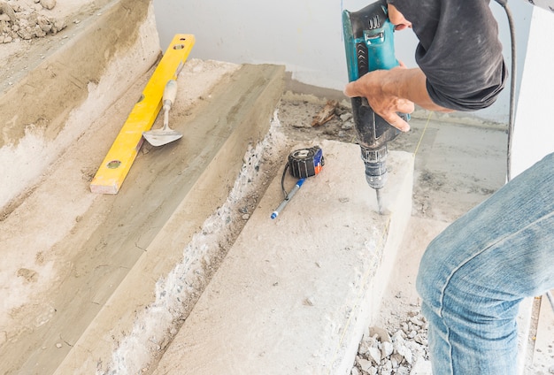 L'homme Travaille Avec Renforcer La Modification De La Structure D'escalier En Béton En Utilisant Une Perceuse à Main