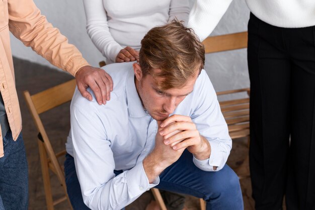 Homme triste assis sur une chaise lors d'une séance de thérapie de groupe