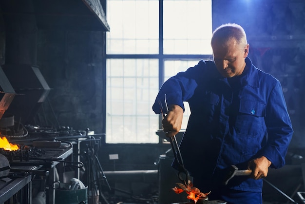 Homme en uniforme bleu foncé travaillant avec un marteau et une pince