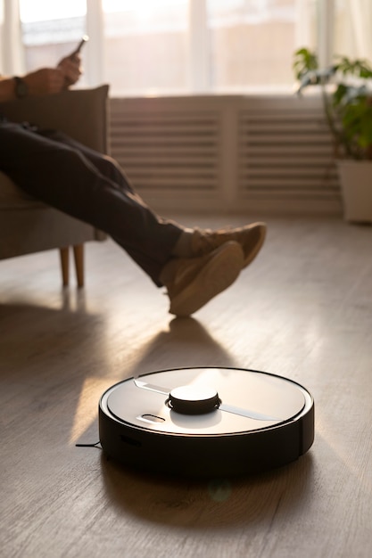 Homme utilisant un aspirateur robot dans le salon