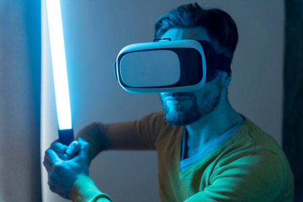 Homme utilisant un casque de réalité virtuelle et jouant avec une épée laser