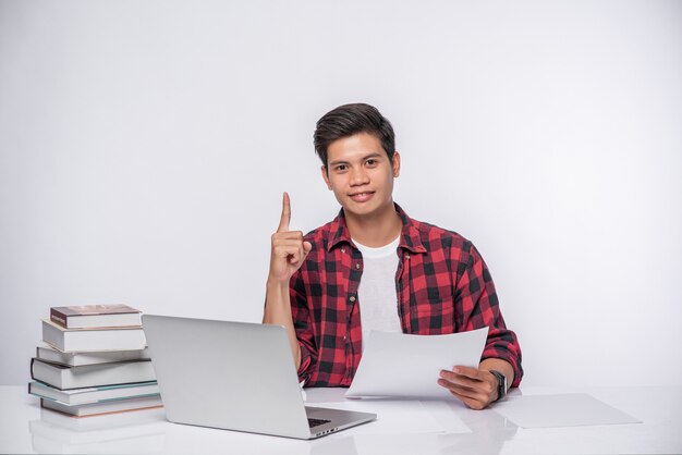 Un homme utilisant un ordinateur portable au bureau et faisant une analyse de documents.