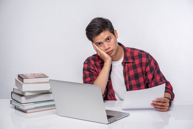 Un homme utilisant un ordinateur portable au bureau et faisant une analyse de documents.