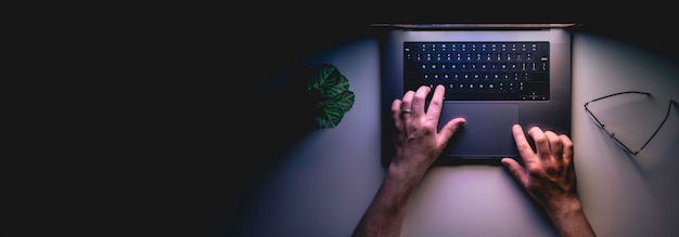 Photo gratuite homme utilisant un ordinateur portable la nuit vue supérieure de la bannière web avec espace de copie