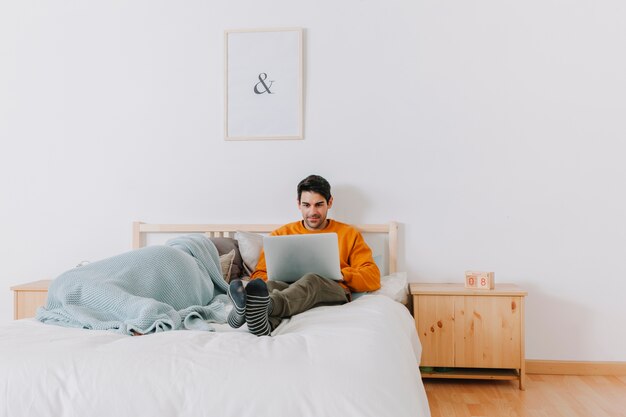 Homme utilisant un ordinateur portable près de la femme endormie