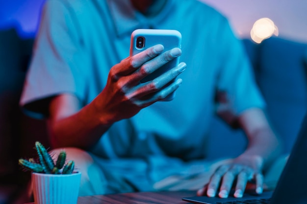 Homme utilisant un ordinateur portable et un smartphone sur le canapé à la maison