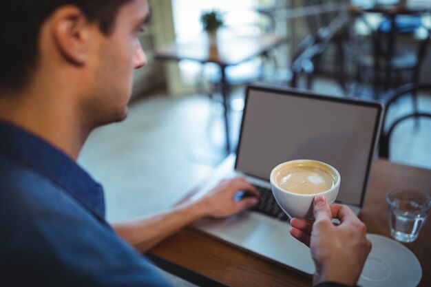 L&#39;homme utilisant un ordinateur portable tout en ayant du café