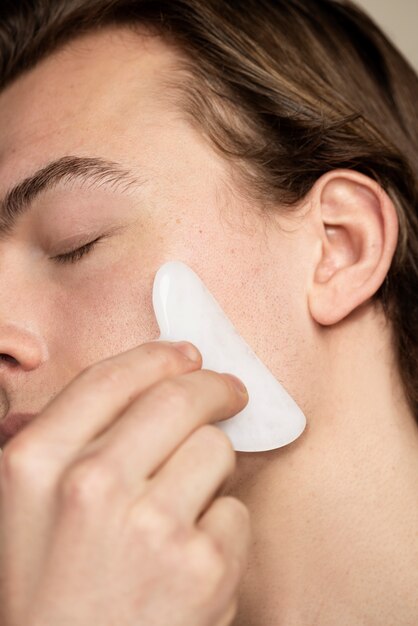 Homme utilisant l'outil gua sha se bouchent