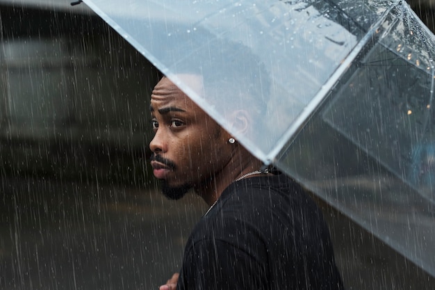 Photo gratuite homme utilisant un parapluie un jour de pluie