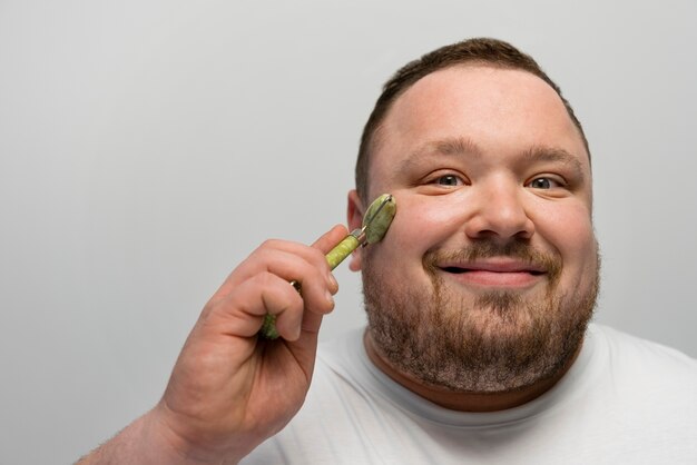 Homme utilisant un rouleau de jade sur son visage pour les soins de la peau