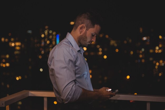 Homme utilisant son téléphone portable sur le balcon