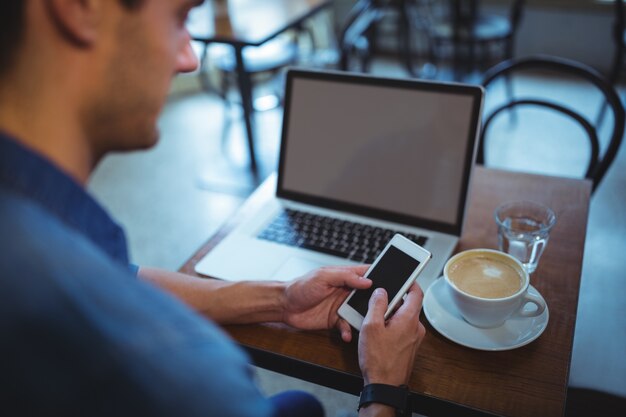 Homme utilisant un téléphone portable dans un café ©