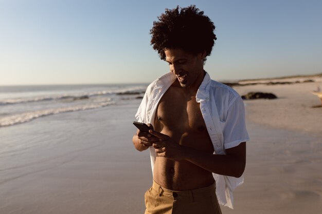 Homme utilisant un téléphone portable sur la plage