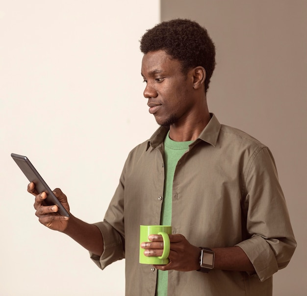 Homme Utilisant Un Téléphone Portable Et Tenant Une Tasse Verte