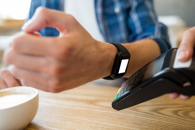 Un homme utilise une montre intelligente pour payer rapidement.