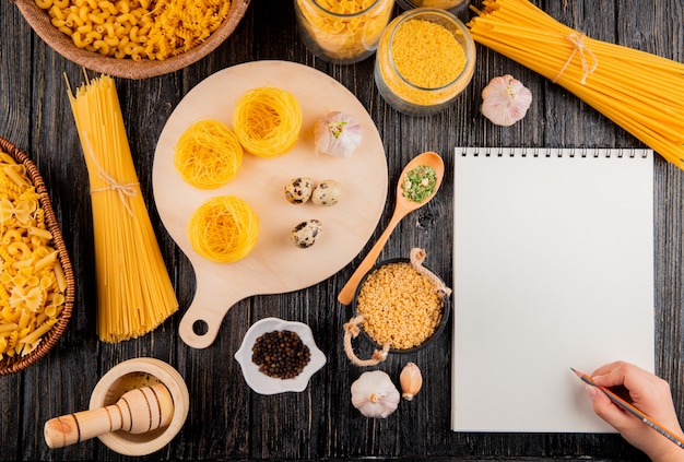 Photo gratuite l'homme va écrire dans le cahier pâtes italiennes spaghetti stelline linguini tagliolini mortier ail vue de dessus copie espace