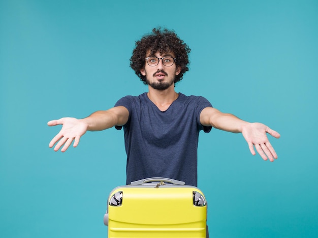 Photo gratuite homme en vacances avec grosse valise sur bleu