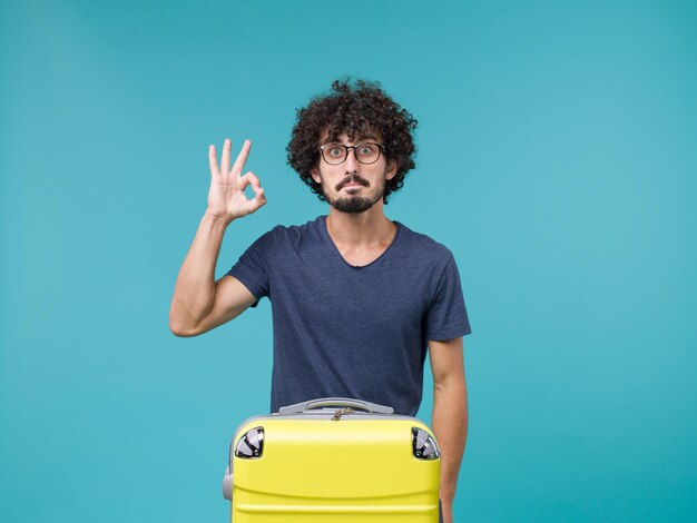 homme en vacances avec grosse valise sur bleu