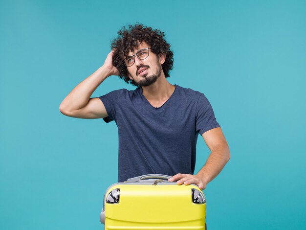 homme en vacances avec une grosse valise pensant au bleu