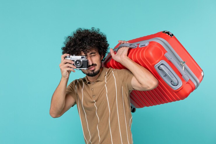 Photo gratuit homme en vacances avec grosse valise prenant des photos avec appareil photo sur bleu