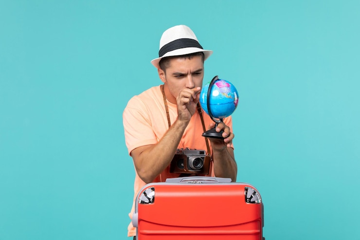 Photo gratuit l'homme en vacances holding globe avec appareil photo sur bleu