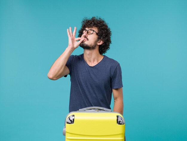 homme en vacances avec sa grosse valise jaune sur bleu