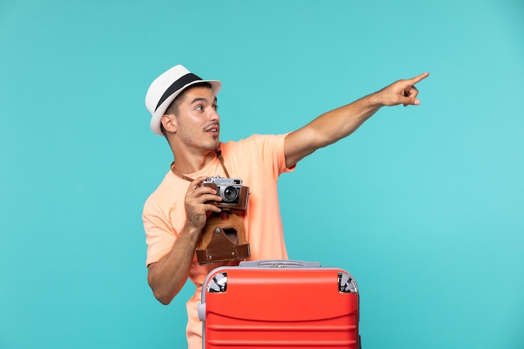 Photo gratuit homme en vacances avec sa grosse valise rouge et appareil photo sur bleu