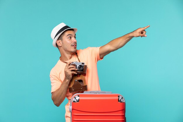 homme en vacances avec sa grosse valise rouge et appareil photo sur bleu