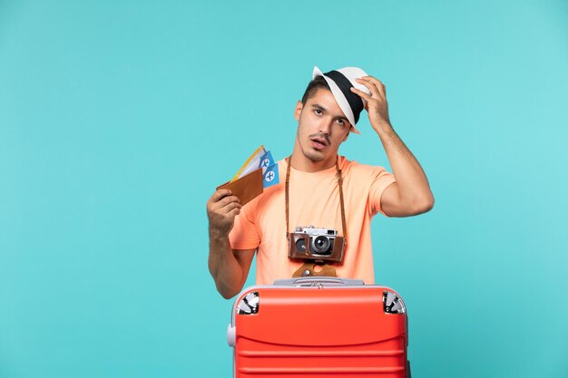 homme en vacances tenant des billets avec un sac rouge sur bleu