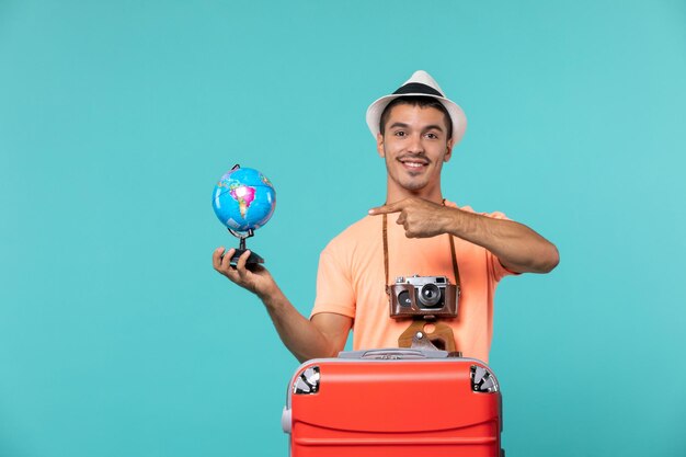 homme en vacances tenant un petit globe sur bleu