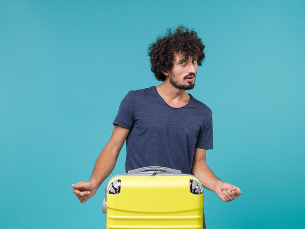 homme en vacances avec valise jaune sur bleu