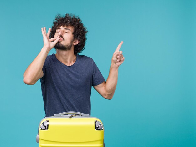 homme en vacances avec valise jaune sur bleu