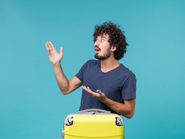 homme en vacances avec valise jaune sur bleu